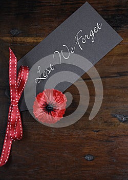 Lest We Forget, Red Poppy Lapel Pin Badge on dark recycled wood - vertical