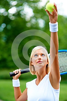 Let the game begin.... A young female tennis player getting ready to serve the ball.