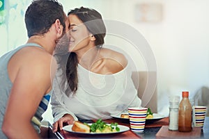 Let it get cold, thats what microwaves are for. a loving young couple kissing at their breakfast table at home.