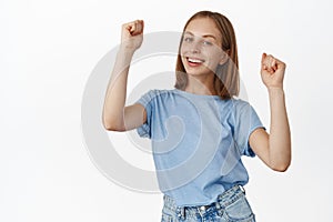 Let have some fun. Happy young woman dancing, girl enjoying party, raising hands up and celebrating, smiling carefree