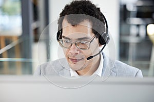 Let me see what I can do for you. a young call centre agent working on a computer in an office.