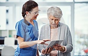 Let me show you...a young female nurse and her senior patient looking at a tablet in the old age home.