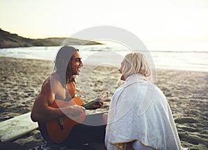Let me sing a song to you babe. Shot of a young happy couple serenading each other during a date on the beach at sunset.