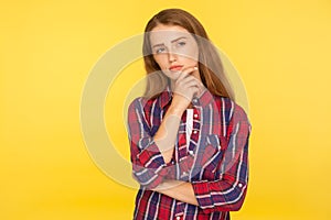 Let me think. Portrait of thoughtful ginger girl in checkered shirt standing with pensive look, pondering and musing