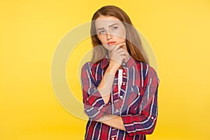 Let me think. Portrait of thoughtful ginger girl in checkered shirt standing with pensive look, pondering and musing photo