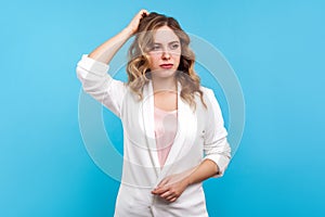 Let me think! Portrait of thoughtful woman scratching head, musing, pondering with confused puzzled face. blue background