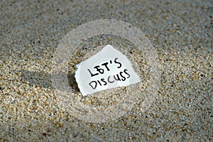 Let\'s Discuss handwritten text on the sand background