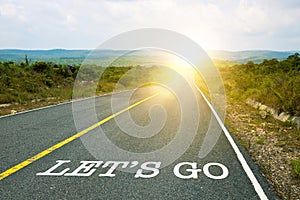 Let`s go, concept photo of asphalt road. Motivational inscription on the road going forward. The beginning of a new path. A