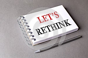 LET\'S RETHINK word on notebook on grey background