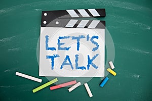 Let's talk. Movie clapper and colored pieces of chalk on a green chalkboard background