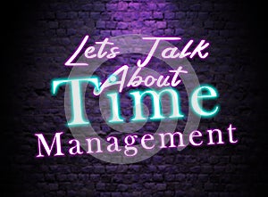 Let`s talk About Time Management Neon Text sign. Glowing Bright lettering on dark brick wall background.