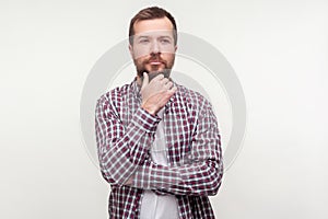 Let`s think! Portrait of pensive bearded man touching his chin pondering serious idea. isolated on white background