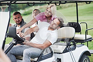 Let`s turn crazy. Family friends having fun riding the golf cart on the field