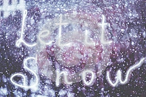 Let it Snow, written by hand on the snowstorm winter background, toned