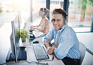 Let us assist you. High angle portrait of a handsome young man working in a call center with a female colleague in the