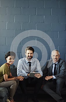 Let us help you achieve success. Cropped portrait of three businesspeople working together on a digital tablet in their