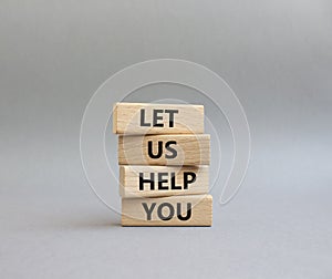 Let us help you symbol. Wooden blocks with words Let us help you. Beautiful grey background. Business and Let us help you concept