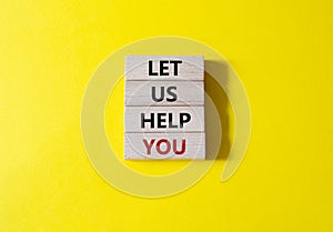 Let us help you symbol. Wooden blocks with words Let us help you. Beautiful yellow background. Business and Let us help you