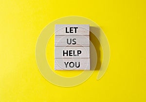 Let us help you symbol. Wooden blocks with words Let us help you. Beautiful yellow background. Business and Let us help you