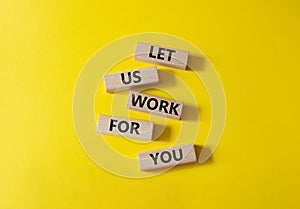 Let us work for you symbol. Wooden blocks with words Let us work for you. Beautiful yellow background. Business and Let us work