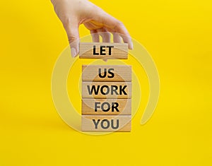 Let us work for you symbol. Wooden blocks with words Let us work for you. Beautiful yellow background. Businessman hand. Business