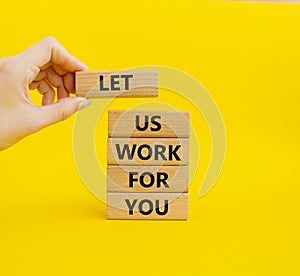 Let us work for you symbol. Wooden blocks with words Let us work for you. Beautiful yellow background. Businessman hand. Business
