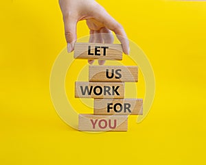 Let us work for you symbol. Wooden blocks with words Let us work for you. Beautiful yellow background. Businessman hand. Business