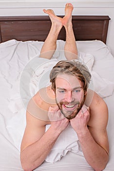 Let your body feel comfortable. Man unshaven handsome happy smiling torso relaxing bed. Man feel full of energy after