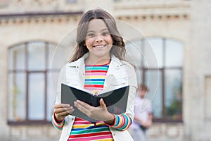 Let your child discover encyclopedia facts. Happy girl hold encyclopedia outdoors. Reading encyclopedia book. Knowledge