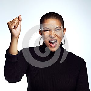 Lets all take a stand. Studio shot of an attractive young woman posing with her arm raised and fist clinched against a photo