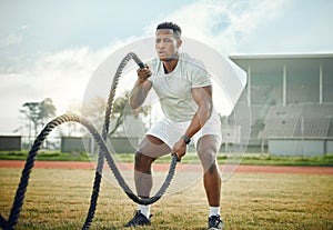 Lets battle it out. Full length shot of a handsome young male athlete exercising with battle ropes outside.