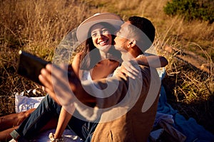 Lets capture this moment. a young couple enjoying the sunset and taking a selfie outside in nature.