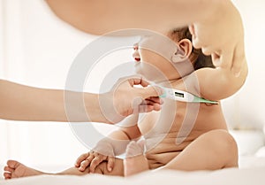 Lets check your temperature. Shot of a paediatrician taking a babys temperature with a thermometer.