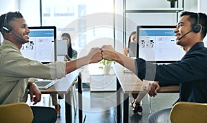 Lets do this, bro. Shot of two handsome salesmen sitting together in the office and giving each other a fist bump.