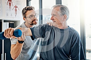 Lets get physical. a friendly physiotherapist helping his mature patient to use dumbbells in a rehabilitation center.