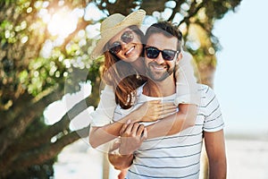 Lets get this summer started. Cropped portrait of a handsome young man giving his girlfriend a piggyback ride at the