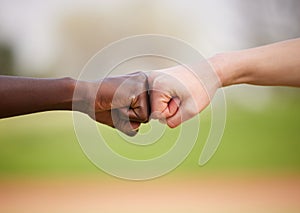 Lets get it on. two unrecognizable female athletes fist bumping outside.