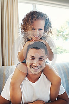 Lets go dad. a handsome young man carrying his daughter on his shoulders in the living room at home.