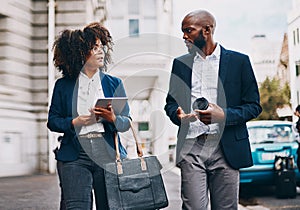 Lets grab some lunch before our next meeting. two businesspeople having a discussion while walking through the city