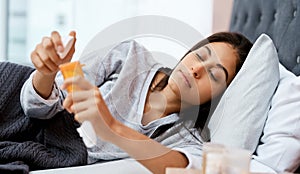 Lets hope this helps. a young woman taking medication while recovering from an illness in bed at home.