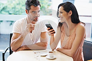 Lets invite our friends to join us. a young woman holding her mobile phone during a coffee date.