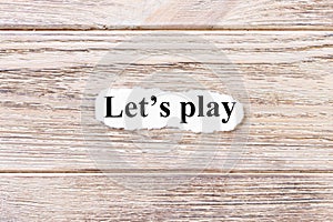 Lets play of the word on paper. concept. Words of lets play on a wooden background