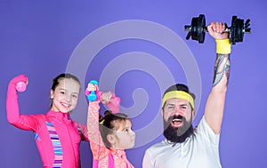 Lets practice. Sports coach and little girls building strength with dumbbells. Father and daughters exercising in gym