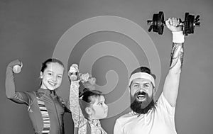 Lets practice. Sports coach and little girls building strength with dumbbells. Father and daughters exercising in gym