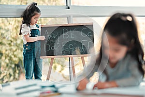 Lets rearrange the alphabet. a young girl writing on a blackboard.