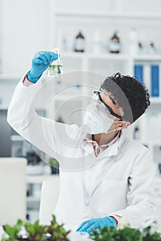 Lets see how were doing here. an attractive young female scientist inspecting a beaker containing a plant and liquid