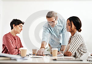 Lets start here. a diverse group of businesspeople sitting together and reading paperwork during a meeting in the office