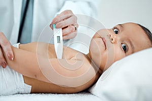 Lets start by taking your temperature. Shot of a paediatrician taking a babys temperature with a thermometer in a clinic