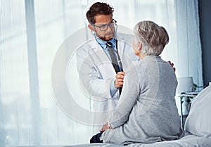 Lets take a listen. a doctor examining a senior patient with a stethoscope in a clinic.