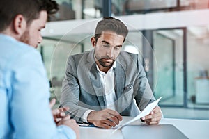 Lets take a look at these numbers. two young businessmen using a laptop while going through paperwork together in a